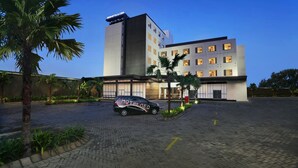 Un hotel moderno con un letrero visible, un patio empedrado y un coche estacionado.