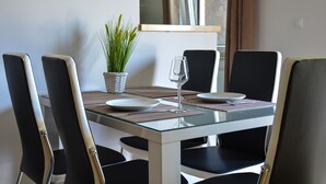 A dining table with four chairs, a glass top, and a potted plant. - Guest House Zevnik (Brezice)