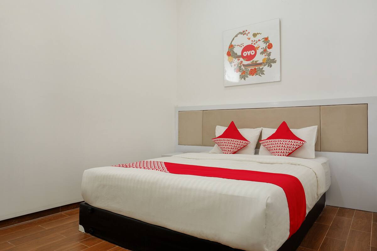 A neatly made bed with a red and white bedspread, two red pillows, and a red throw blanket.
