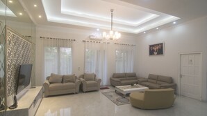 A spacious living room with two sofas, a coffee table, and a TV on a stand. - Royal Homy Syariah (Depok)