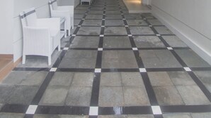 A hallway with a checkered floor, white walls, and a staircase in the distance. - Royal Homy Syariah (Depok)