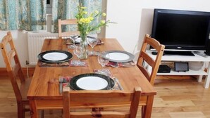 Une table à manger dressée avec des assiettes, des couverts et un vase rempli de fleurs.