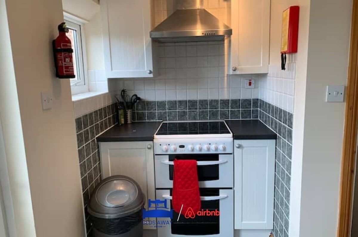 A compact kitchen with a stove, oven, and a fire extinguisher mounted on the wall.