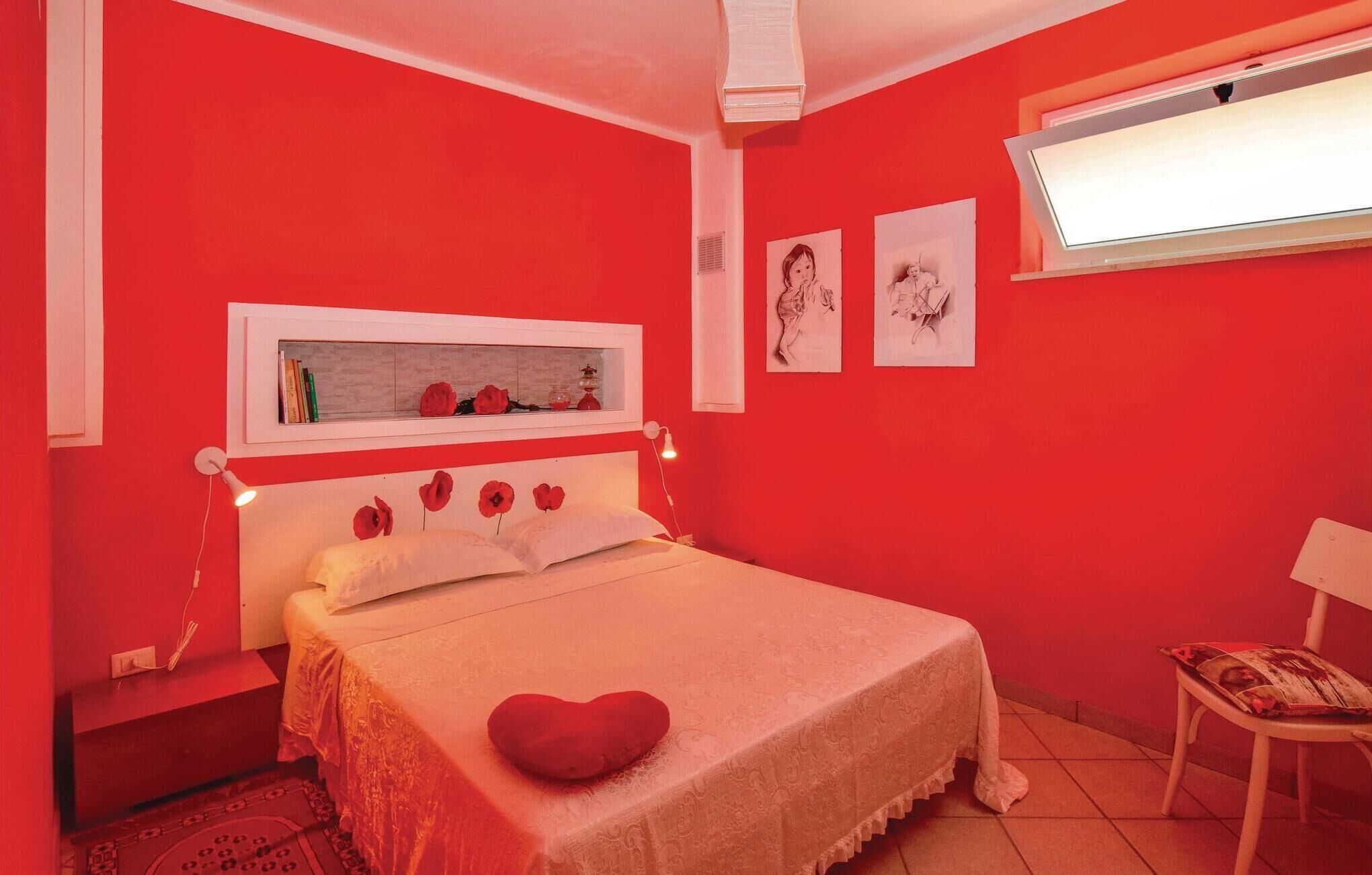 A room with a bed, a chair, and artwork on the wall.