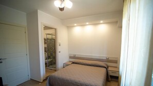 Un dormitorio con cama, mesitas de noche, ducha y puerta.