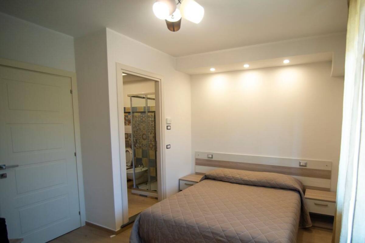 A bedroom with a bed, bedside tables, a shower, and a door.