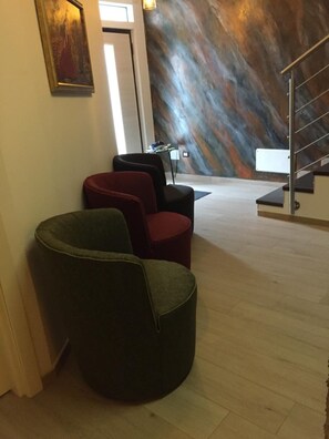 A modern interior with a staircase, a painting on the wall, and three upholstered chairs. - B&B Terra Mare (Trecchina)