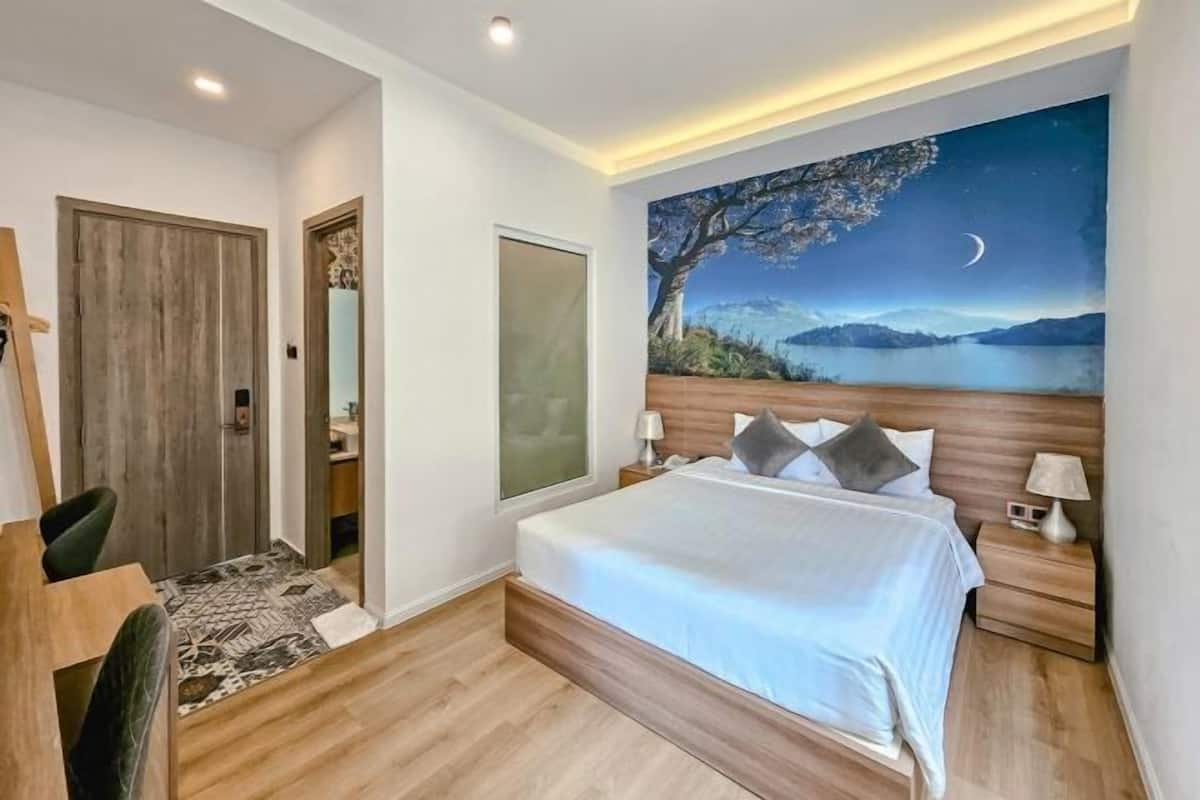 A bedroom with a bed, bedside tables, a nightstand, a desk, and a chair.