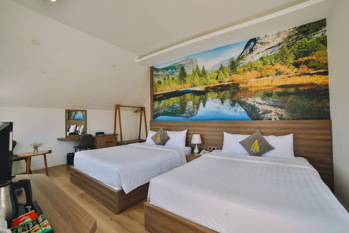 A hotel room with two beds, a desk, a TV, and a large mountain landscape painting on the wall.