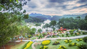 A landscaped garden with pathways, a pond, and a view of distant mountains. -  NATURE LAND 2 - Song Anh Hotel Dalat (Xuan Huong - Da Lat)