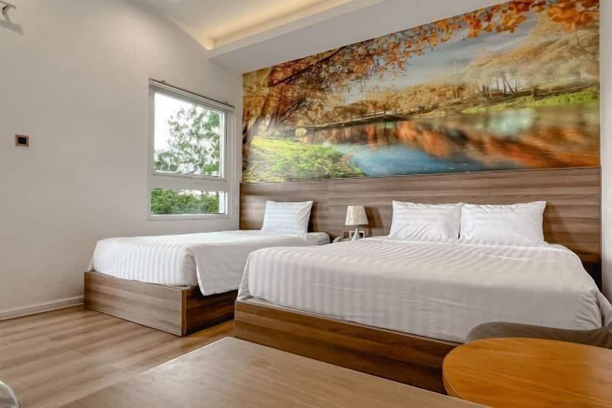 A hotel room with two beds, a large window, and a painting of a landscape.