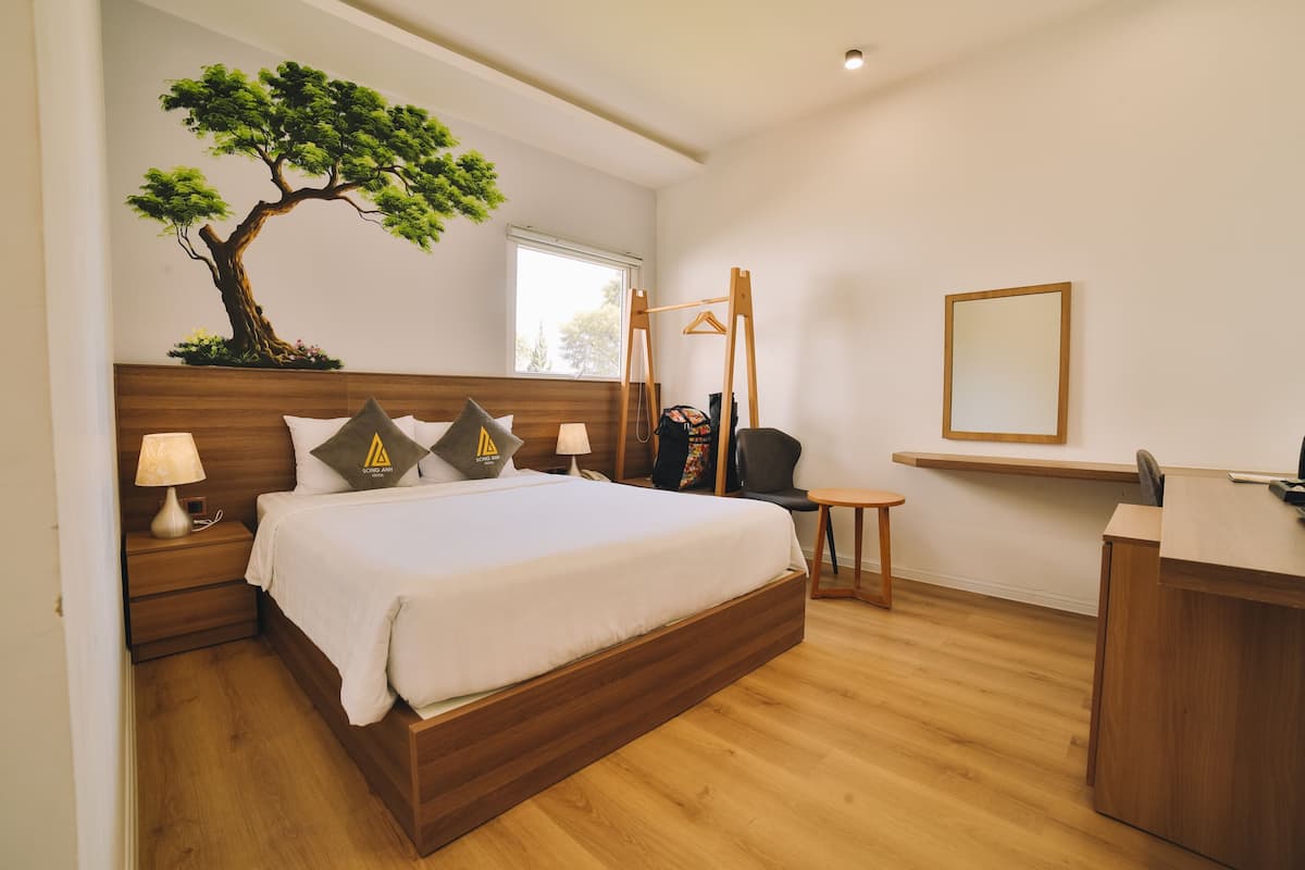 A modern bedroom with a wooden bed, bedside tables with lamps, a desk, and a hanging chair.