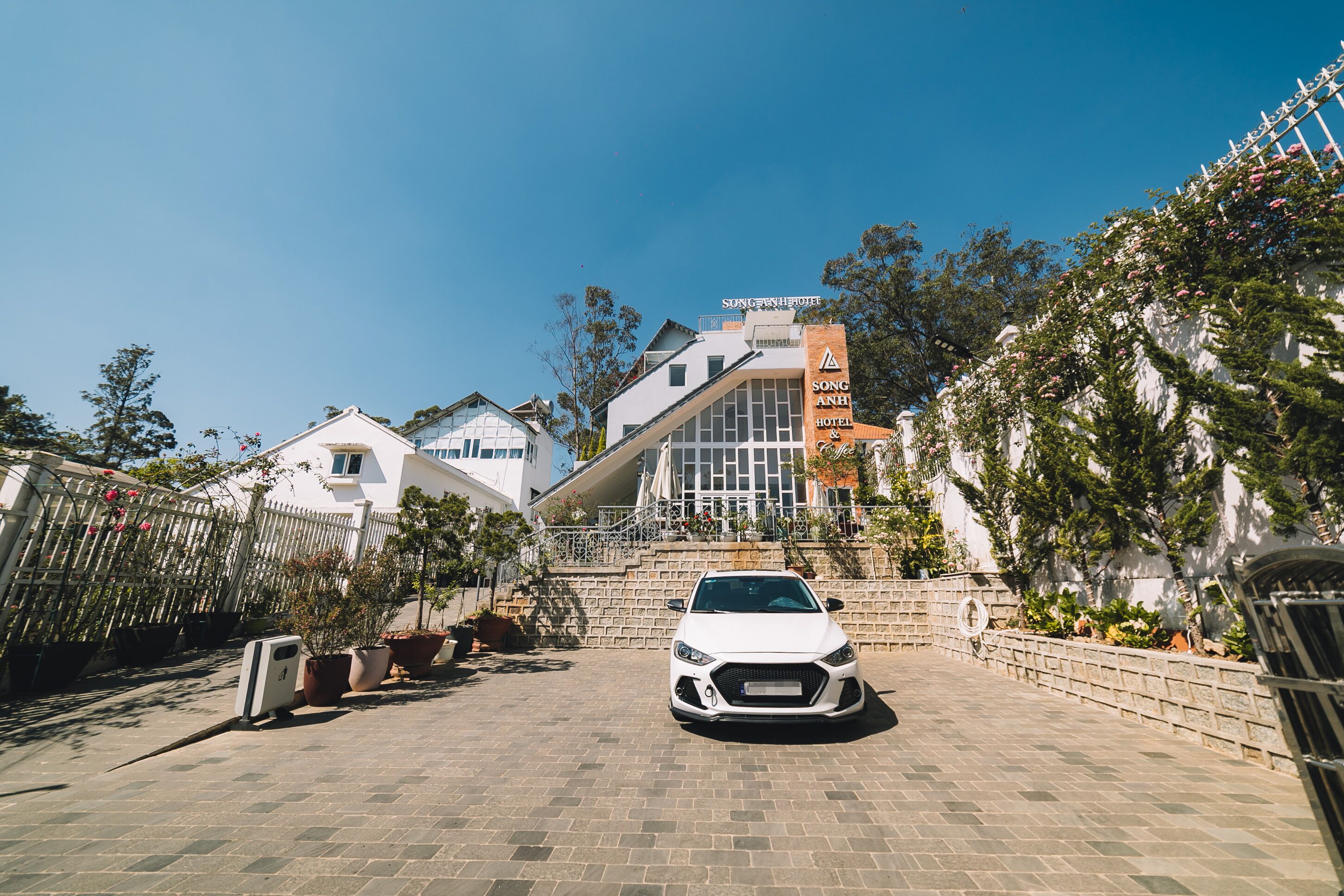 A white car parked in front of a hotel with a clear blue sky.