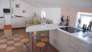 A compact kitchen with a white countertop, four stools, and a dining table. - Studio with sea view and air conditioning. (Rovinj)