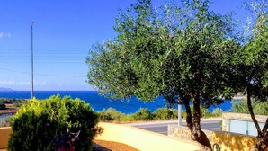 A coastal view with a stone wall, a table with a potted plant, and a tree. - Villa Paradise (Agios Nikolaos)
