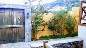 A rustic wooden gate with a stone wall and climbing plants. - Villa Paradise (Agios Nikolaos)