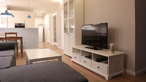 Een moderne woonkamer met een flatscreen televisie, een bank, een salontafel en een tv-meubel met opbergladen.