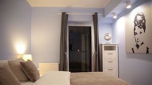 Een slaapkamer met een bed, een nachtkastje, een lamp, een kledingkast en een deur naar een balkon.
