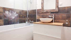 Een moderne badkamer met een glazen douchecabine, een houten wastafelmeubel en een grote spiegel.