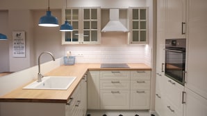 Een moderne keuken met witte kastjes, een houten aanrechtblad, een roestvrijstalen spoelbak en een inbouwoven.