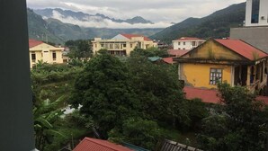 A residential area with houses, a river, and mountains in the background. - Cao Nguyen Guesthouse (Yen Minh)