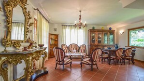 A dining area with a round table and chairs, a chandelier, and a cabinet with glass doors. - Nice home in Camaiore -LU- with private swimming pool, can be inside or outside (Camaiore -LU-)