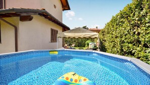 A swimming pool with a clear blue mosaic tile design, surrounded by a hedge and a building with a tiled roof. - Nice home in Camaiore -LU- with private swimming pool, can be inside or outside (Camaiore -LU-)