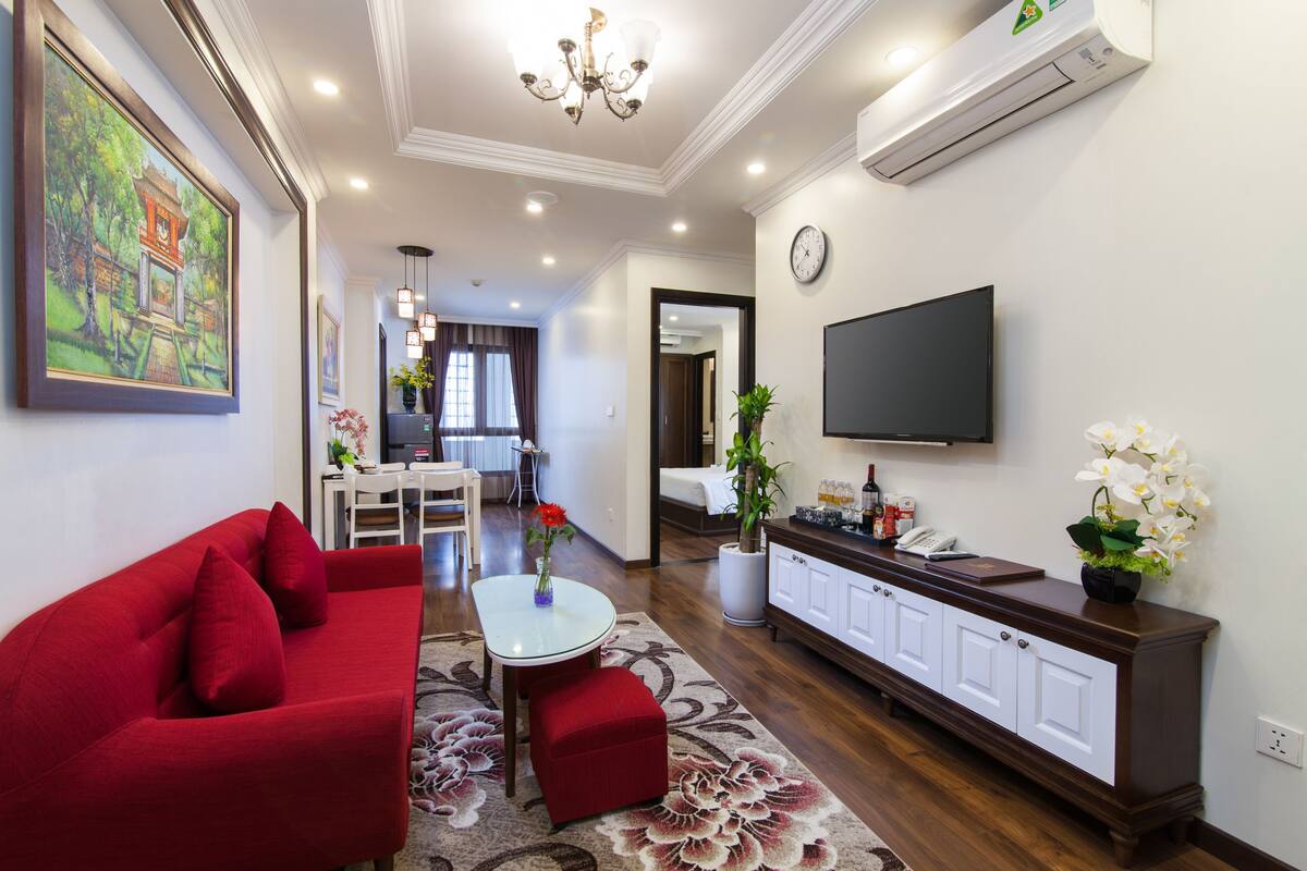 A living room with a red sofa, a white coffee table, and a TV mounted on the wall.