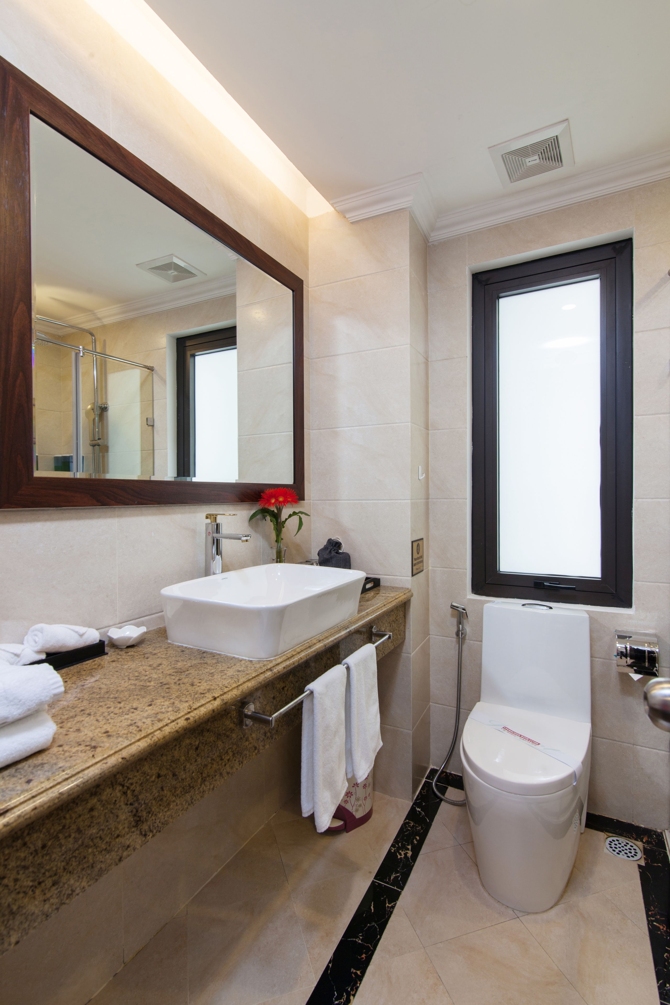 A modern bathroom with a large mirror, a white sink, a toilet, and a shower.