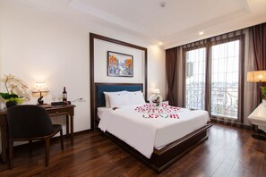 A hotel room with a large bed, a desk with a chair, a potted plant, and a window with curtains. - Hanoi Central Hotel & Residences (Hanoi)