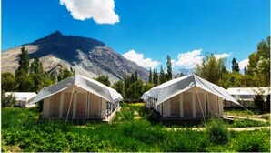 Two tents in a grassy area with a mountain in the background. - TIH Magpie Camp (Leh)