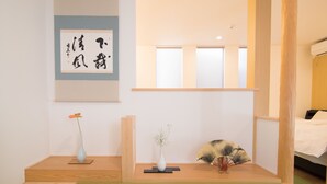 A minimalist room with a wooden bed, a wall-mounted artwork, and two vases on a wooden shelf. - Kyo-Anthu Inn (Kyoto)