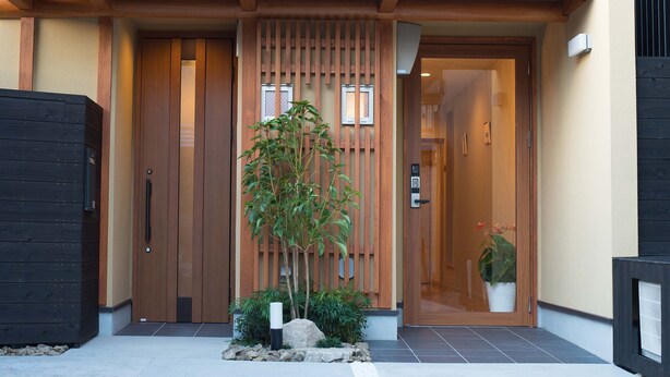A modern building with a wooden entrance, a small garden with a tree, and a glass door. - Kyo-Anthu Inn (Kyoto)