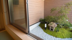 A modern interior with a sliding glass door, a small garden area with a rock feature, and a wooden bench. - Kyo-Anthu Inn (Kyoto)