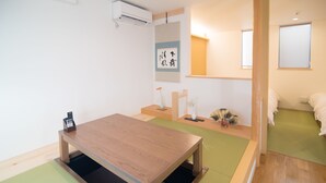 A room with a wooden table, a green mat, a small desk with a vase, and a cat. - Kyo-Anthu Inn (Kyoto)