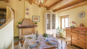 Uma sala de jantar com uma mesa redonda para quatro pessoas, lareira e teto de madeira.