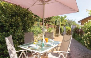An outdoor dining area with a table and chairs under a large umbrella, surrounded by lush greenery and a stone staircase. - Amazing home in Massa (MS) with house a mountain view (Massa (MS))