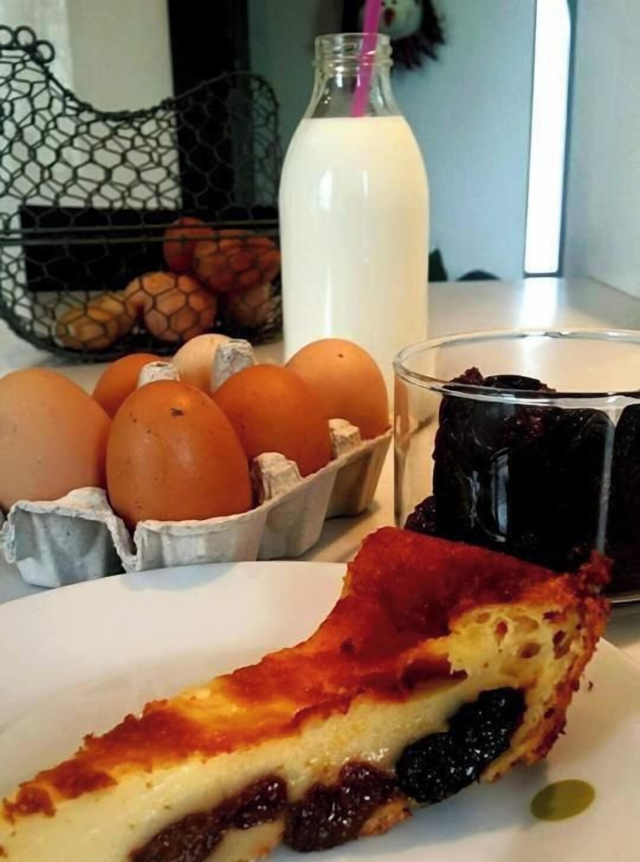 A slice of cheesecake on a plate, a glass of milk, and a bowl of fruit.