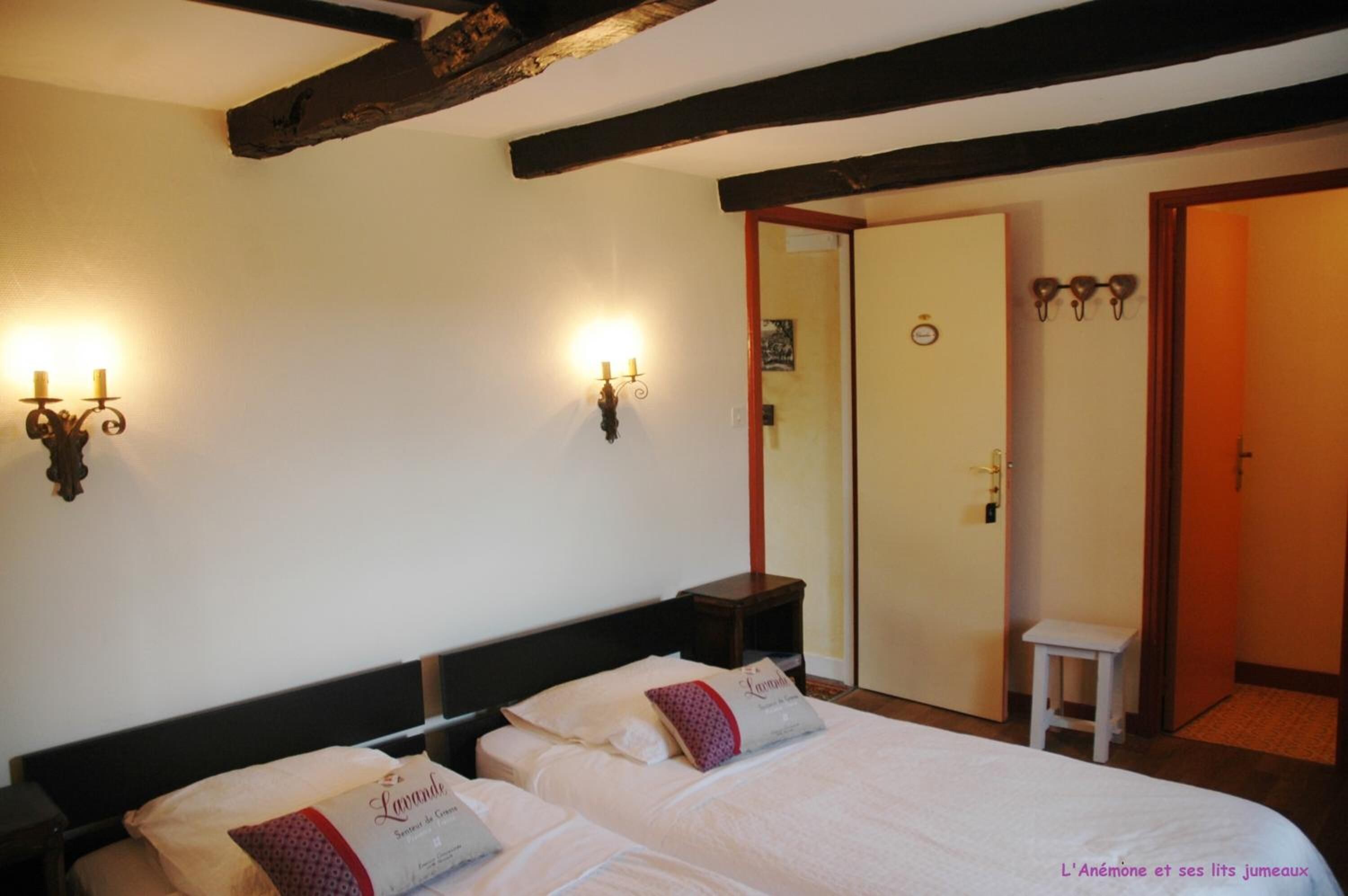 Een hotelkamer met twee bedden, een houten plafond en wandlampen.