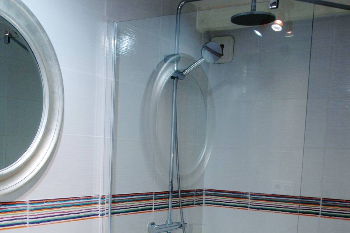 A bathroom with a glass-enclosed shower, a white sink, and a mirror.