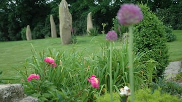Een tuin met bloemen, een pad van stenen en stenen monumenten.