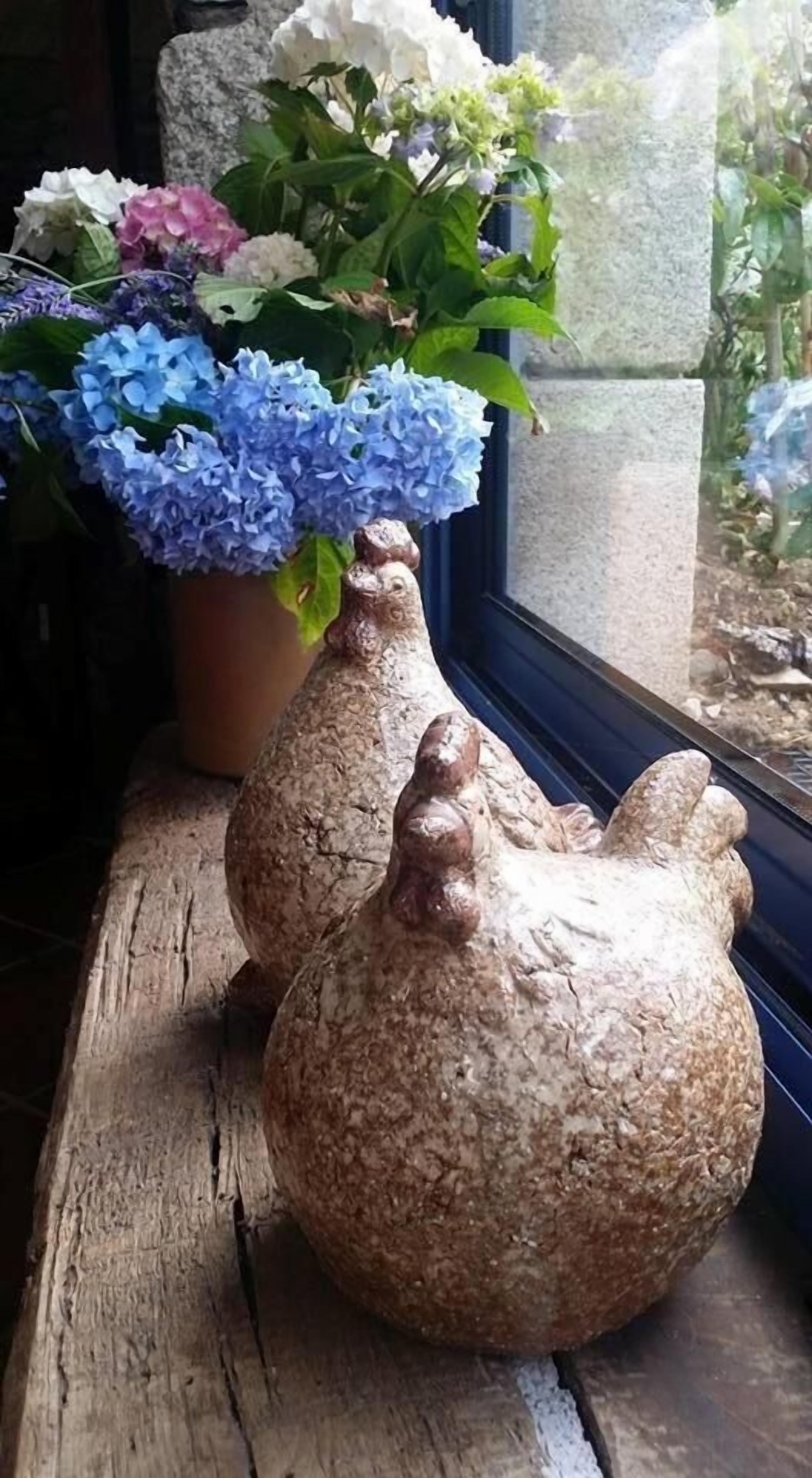 Two ceramic vases with a textured surface, placed on a wooden ledge by a window.