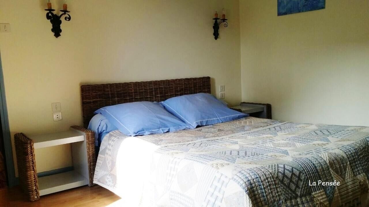 Un dormitorio con una cama, dos mesitas de noche y una lámpara de pared.