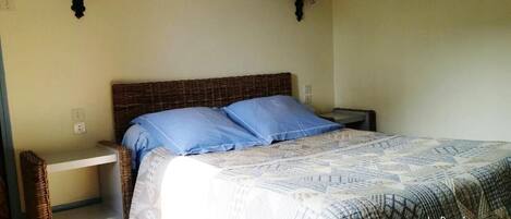 Un dormitorio con una cama, dos mesitas de noche y una lámpara de pared.