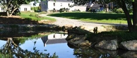 A serene lakeside setting with a stone building, a clear reflection in the water, and a well-maintained grassy area.