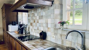 Una cocina con un ventanal grande, un lavamanos de acero inoxidable y una cafetera sobre la encimera.