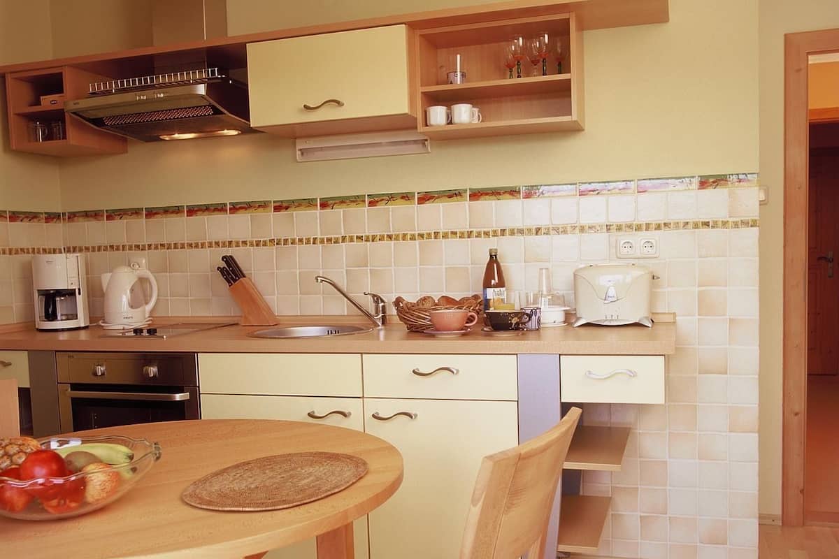 A compact kitchen with a sink, coffee maker, toaster, and a fruit bowl on the counter.