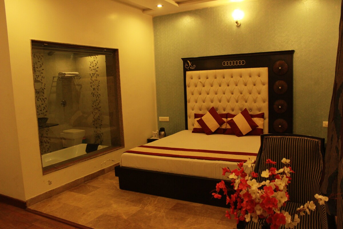 A bedroom with a large bed, a glass shower enclosure, and a view of the bathroom.