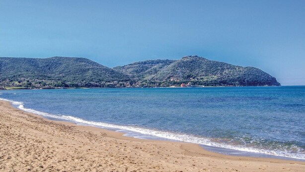 A beach with a clear view of a mountain range in the background.