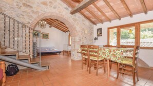 A rustic interior with a dining area, a staircase, and a stone wall.